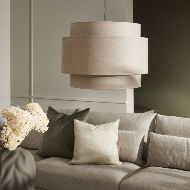 Beige taklampa ovanför soffa med kuddar och vas