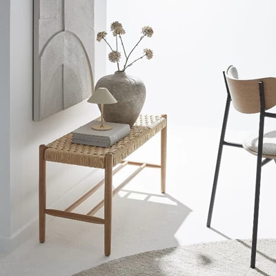 Flätad bänk med dekorativ vas och liten bordslampa