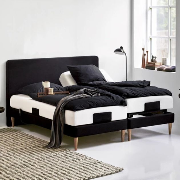 Svart ställbar säng med träben och svart sänglinne