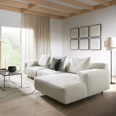 Ljust vardagsrum med vit soffa, trädetaljer och stora fönster.