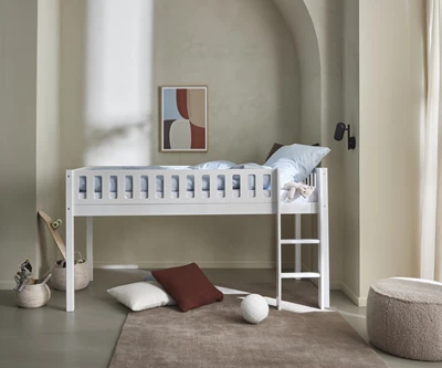 Højseng til børn i lyst værelse med stige og hyggelig gulvplads med puder.