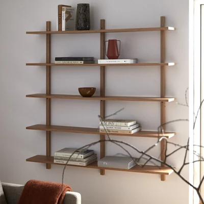 Vägghylla i trä på väggen med diverse prydnadssaker ovanpå