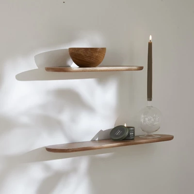 Enkla vägghyllor i trä med bland annat en träskål och ett doftljus ovanpå