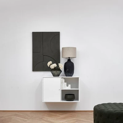 Minimalistisk förvaring med vit hylla och svart tavla, samt inredning i matchande färger