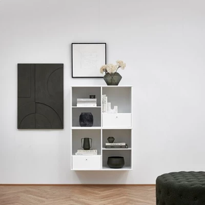 Minimalistisk förvaring med två vita hyllor och en svart och en vit tavla, samt inredningsdetaljer i liknande färger.