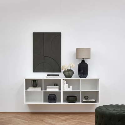Minimalistisk förvaring med en vit hylla och en svart tavla, samt inredningsdetaljer i liknande färger.