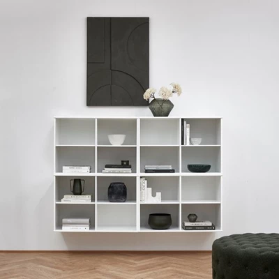 Minimalistisk förvaring med vita hyllor som är kombinerade och en svart tavla, samt inredningsdetaljer i liknande färger.