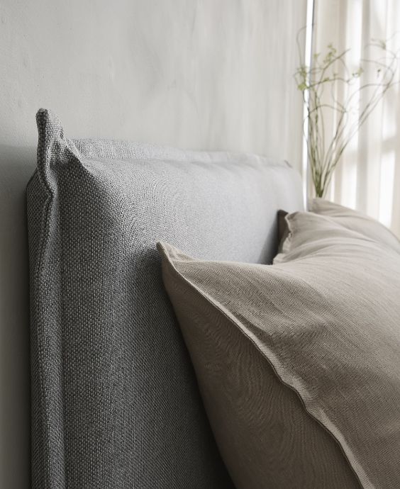 Närbild av sänggavel med kudde framför