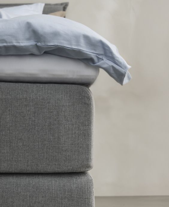 Närbild av grå säng med blått sänglinne