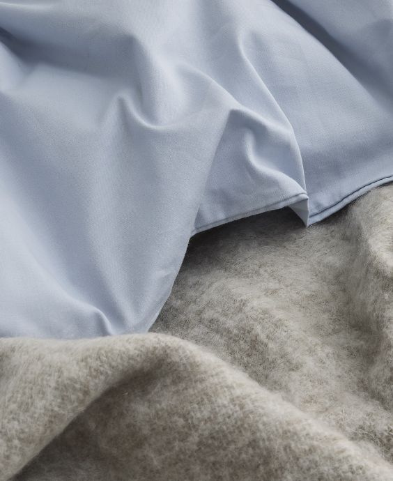 Närbild av blått sänglinne och grå filt