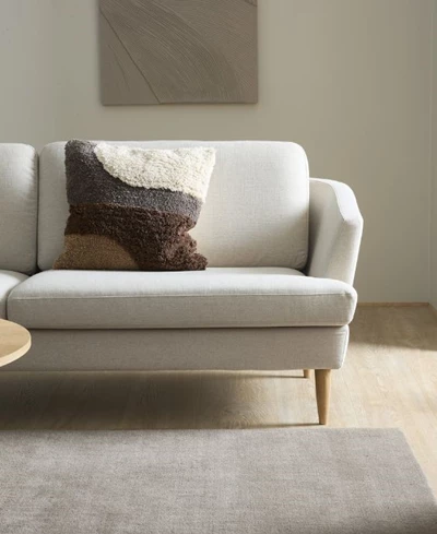 Stilren och klassisk soffa i ljusa nyanser stående på trägolv med en matta framför