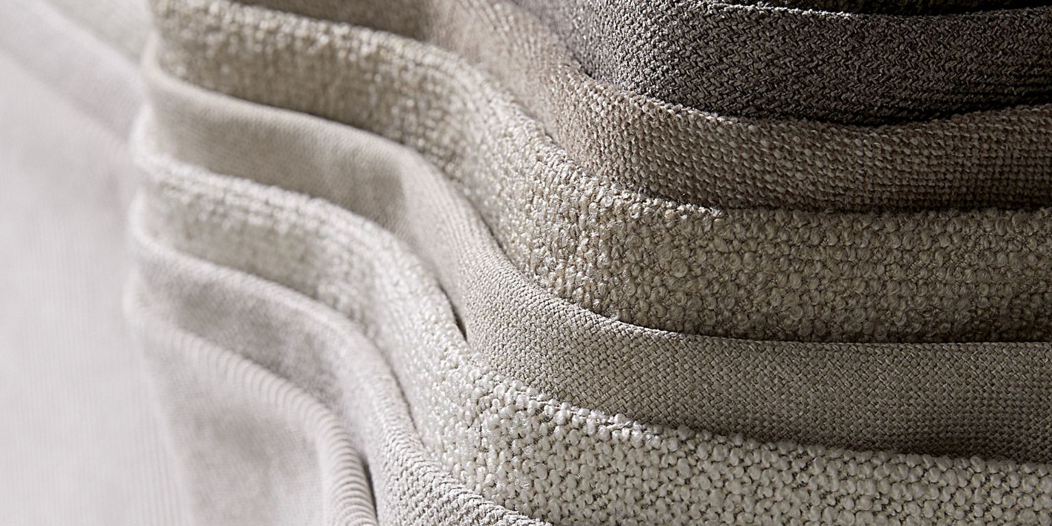 Närbild på en stapel av grå tygstolar som framhäver tygets struktur och kvalitet.