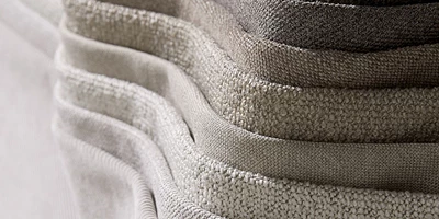 Design uden navn - 2025-01-06T135719.310.jpg Närbild på en stapel av grå tygstolar som framhäver tygets struktur och kvalitet.