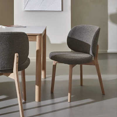 Omfamnande matsalsstolar i grått med böjt ryggstöd och trästomme