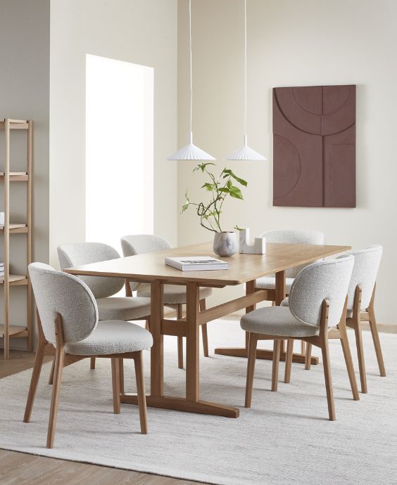 Mysigt matområde med ett avlångt träbord och stoppade stolar i grått runtom