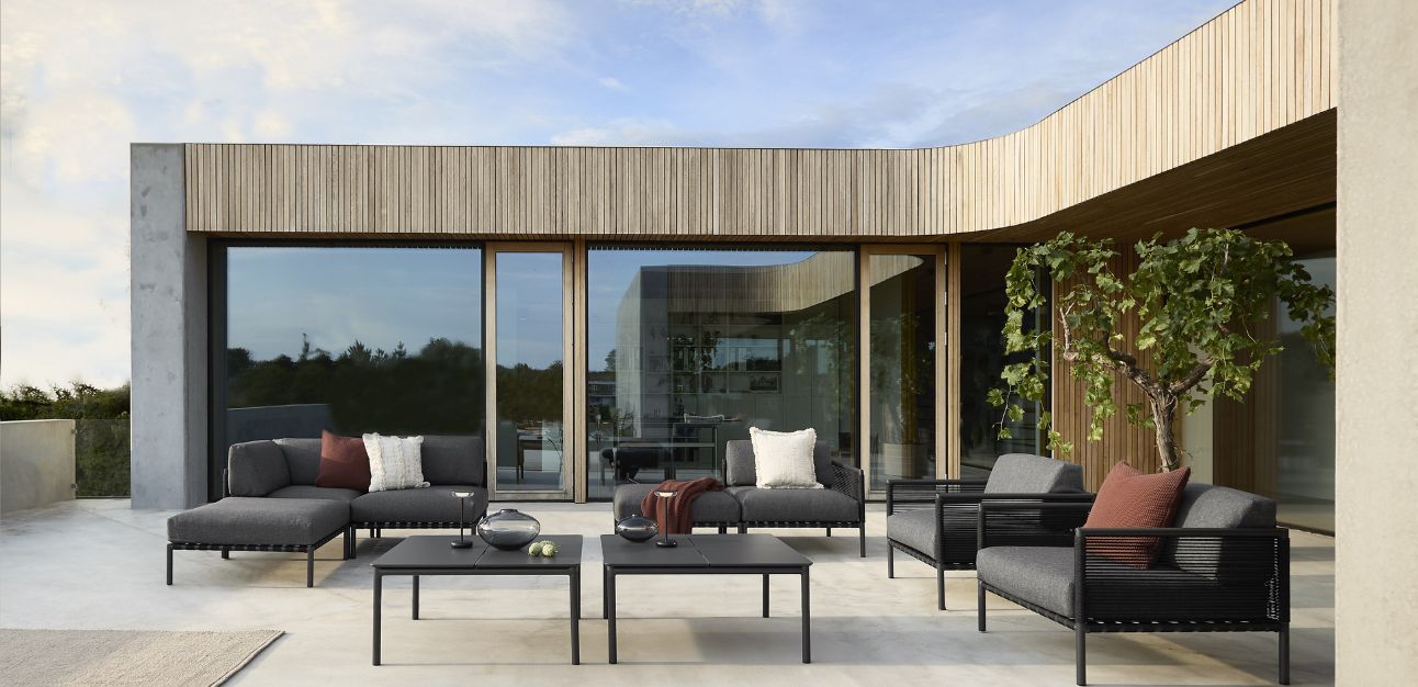 Terrass med svart trädgårdsgrupp framför modern byggnad