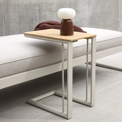 Träbord bredvid modern solstol på en terrass med rött täcke.