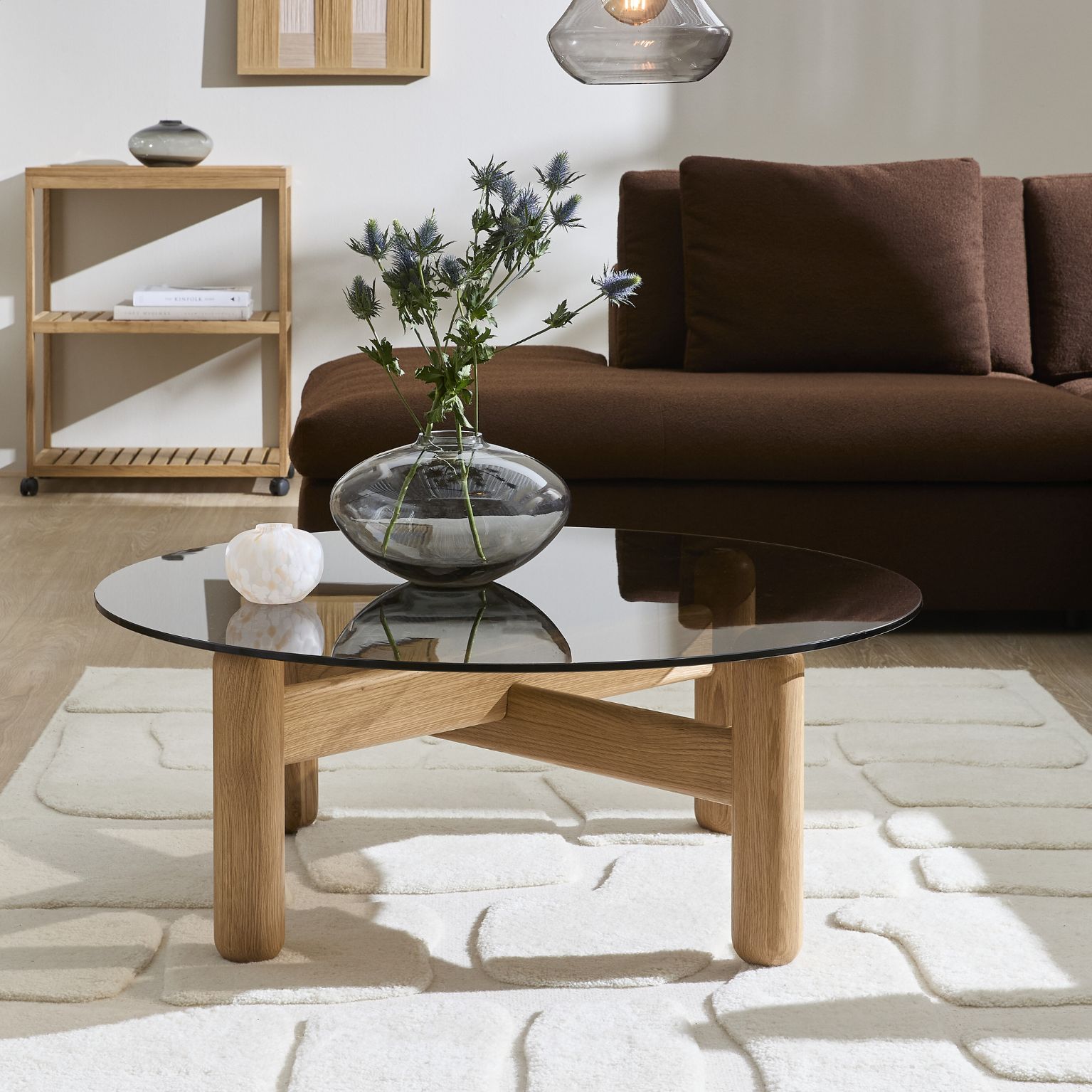 Vardagsrumsmiljö med ett soffbord i centrum. Soffbordet har en glasskiva och ben i ek.