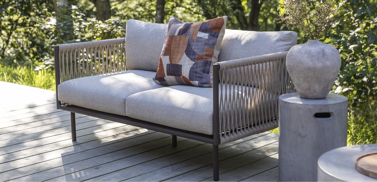 2-sits loungesoffa med grå dynor stående på terrass