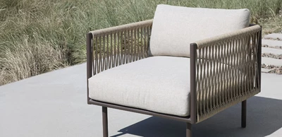 lænestol.jpg Loungefåtölj med grå dynor och flätad sits och rygg