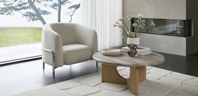 Design uden navn - 2025-02-13T122345.718.jpg Loom loungestol med slank metallram i en stilren vardagsrumsinredning med stora fönster, utsikt över naturen och ett elegant, organiskt soffbord.