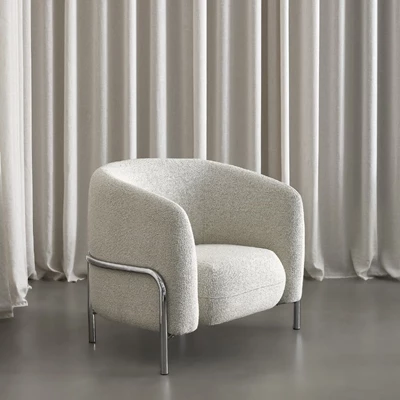 Grå fåtölj med rund design framför gardiner