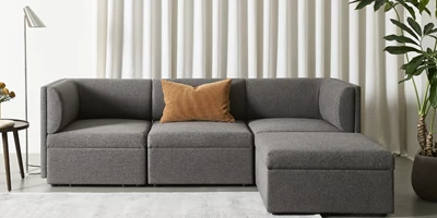 Design uden navn - 2025-02-21T125834.090.jpg Modern, gråaktig soffa med rundade armstöd och ryggkuddar.