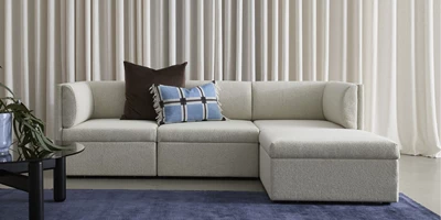 Design uden navn - 2025-02-21T125640.238.jpg Modern, vitaktig soffa med rundade armstöd och ryggkuddar.