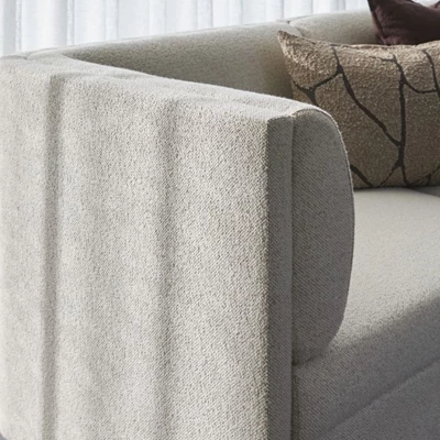 Närbild av rundat armstöd på en vitaktig soffa.