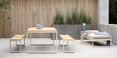 Design uden navn - 2025-02-25T112927.577.jpg Minimalistiskt utomhus loungeområde med moderna trä- och metallbord och bänkar, placerade på en betongterrass.