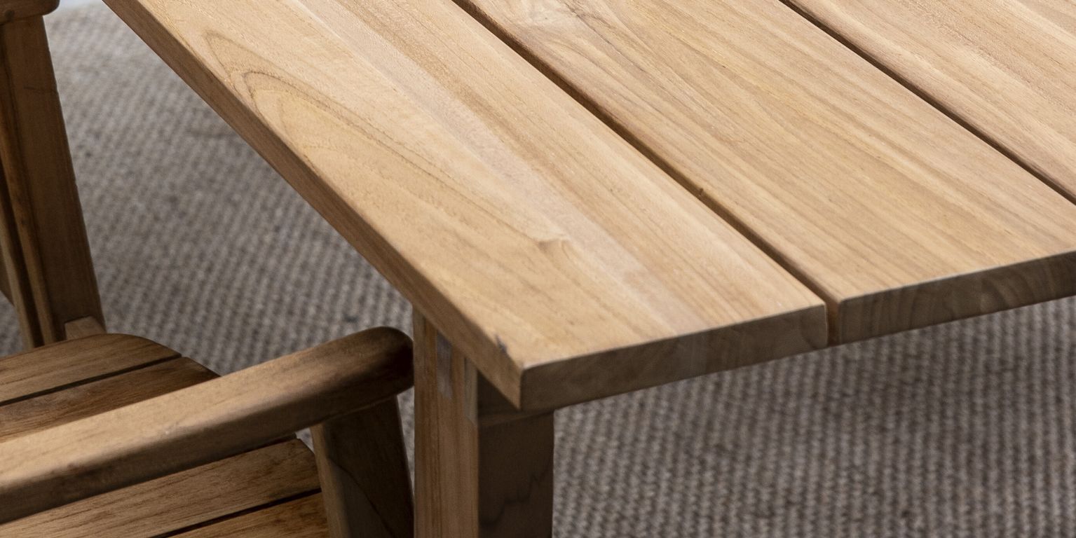 Närbild av hörnet av ett träbord som visar strukturen på träplankorna och fogarna vid bordbenet.