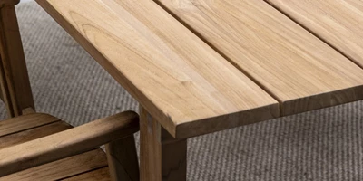 Design uden navn - 2025-02-25T113311.855.jpg Närbild av hörnet av ett träbord som visar strukturen på träplankorna och fogarna vid bordbenet.