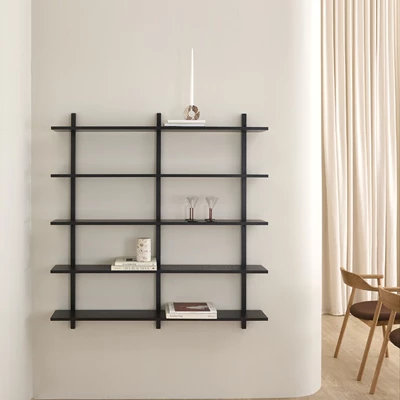 Modern svart vägghylla med flera hyllplan i ett ljust vardagsrum.