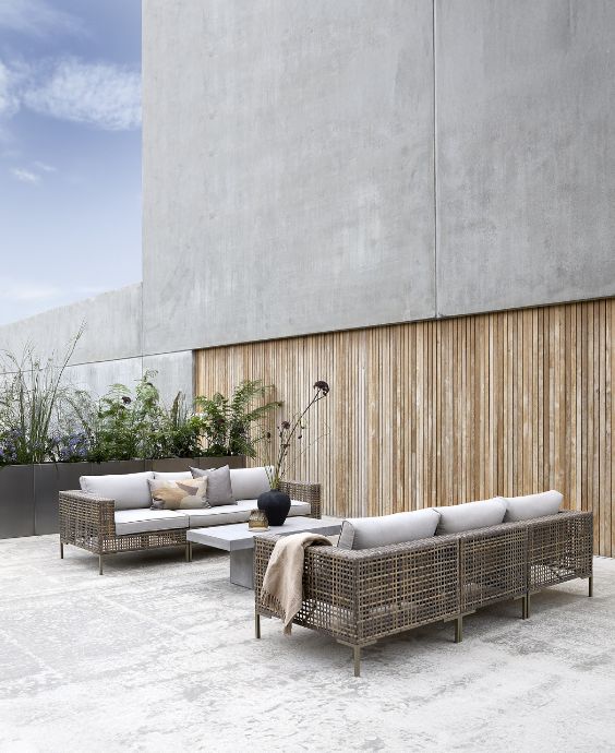 Elegant utomhus loungeområde med två soffor och ett bord, inrett mot en träklädd vägg.