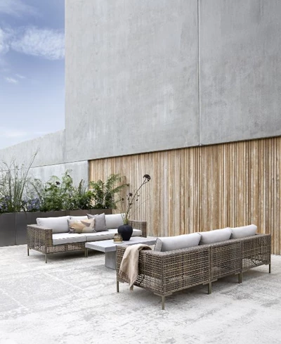 Elegant utomhus loungeområde med två soffor och ett bord, inrett mot en träklädd vägg.