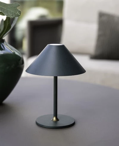 En modern, svart bordlampa på ett lågt bord utomhus i skymningen.