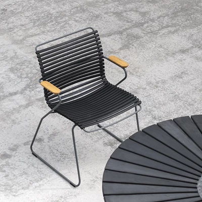 Enskild modern flätad stol med metallben och träarmstöd på en betongyta