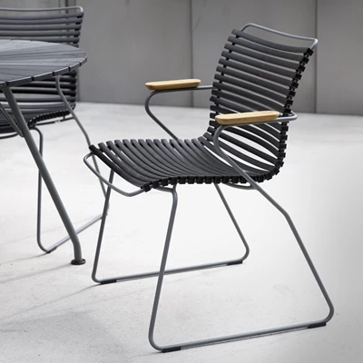 Moderna flätade stolar med träarmstöd och svart sitsdyna, placerade på en betongyta