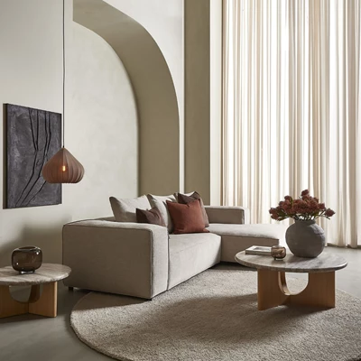 Modernt vardagsrum med välvd vägg, beige soffa, trämöbler och en harmonisk färgpalett med mjuka nyanser och naturligt ljus från stora fönster.