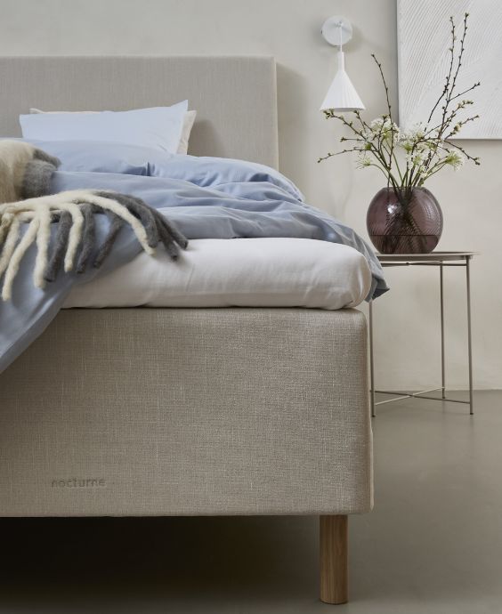 Modernt sovrum med boxsäng, inrett med blått och beige sängkläder och minimalistisk dekor