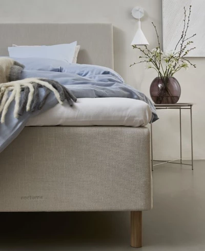 Modernt sovrum med boxsäng, inrett med blått och beige sängkläder och minimalistisk dekor