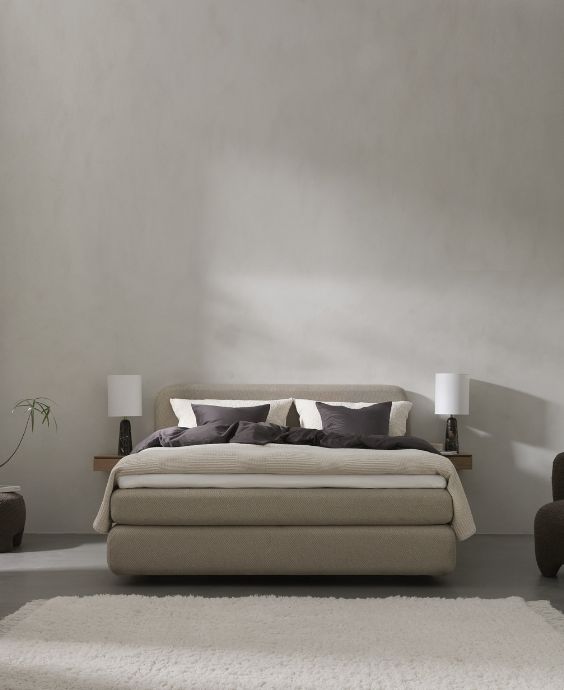 Kompakt boxsäng i ett litet sovrum med enkel inredning och beige väggfärg