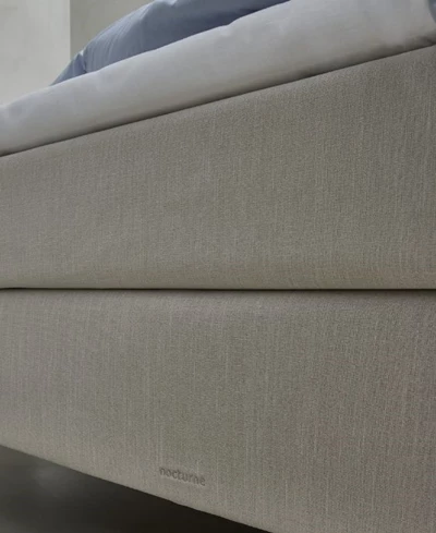Närbild av en beige boxmadrass som visar texturernas detaljer och varumärket Nocturne broderat i tyget.