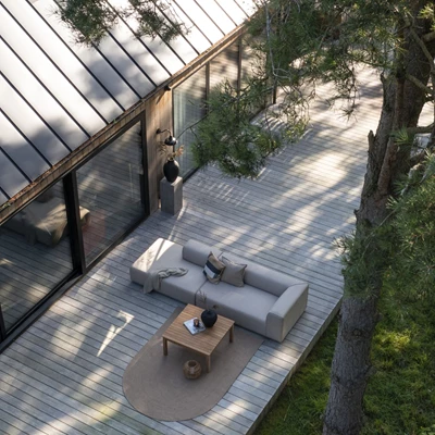 Luftfoto av ett stilfullt utomhus loungeområde med QuickDry Foam möbler placerade på en träterrass, omgiven av träd och med utsikt över en modern byggnad