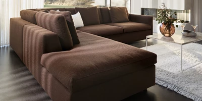 Design uden navn - 2025-03-20T130356.705.jpg Brun schäslongsoffa tillsammans med vit matta och minimalistiskt soffbord