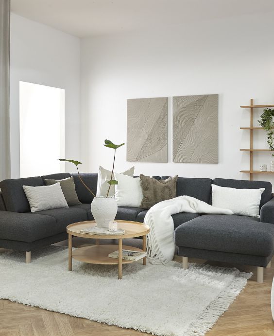 Stor familjesoffa i vardagsrummet tillsammans med bland annat soffbord, matta och bokhylla