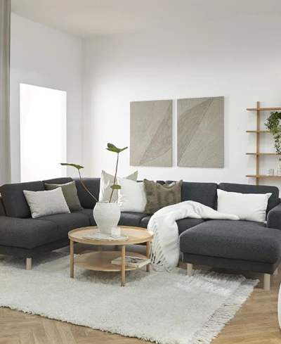 Stor familjesoffa i vardagsrummet tillsammans med bland annat soffbord, matta och bokhylla