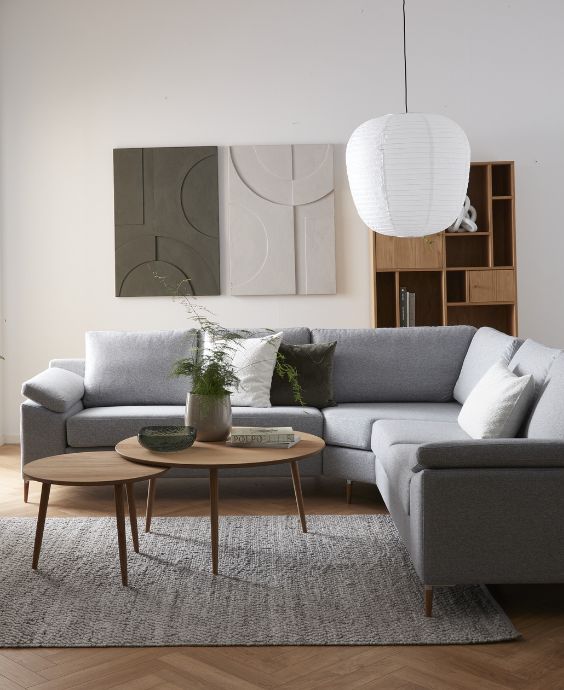 Grå hörnsoffa placerad i vardagsrummet tillsammans med soffbord, matta och bokhylla.