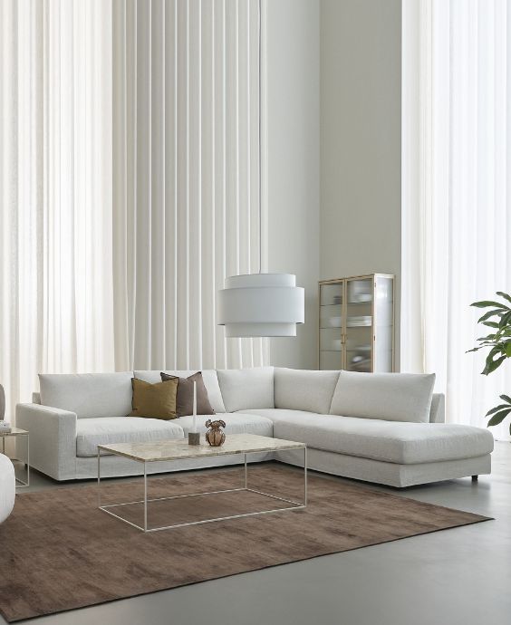 Vit hörnsoffa placerad på ett rödaktigt matta.