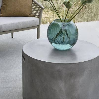 En grönaktig vas stående på ett lounge-soffbord i fibercement
